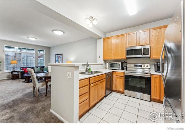 kitchen featuring light carpet, kitchen peninsula, sink, and stainless steel appliances