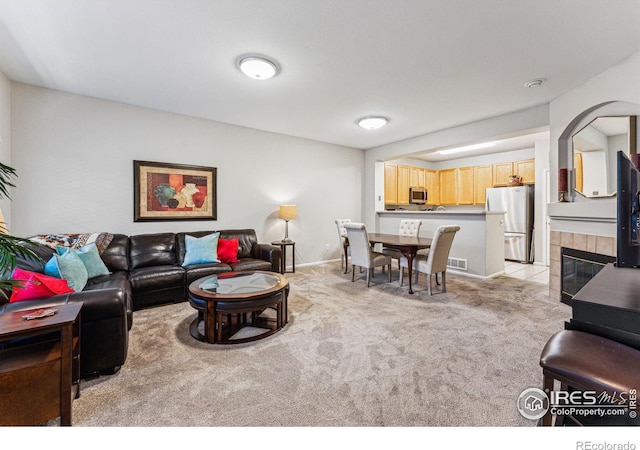 carpeted living room with a tile fireplace