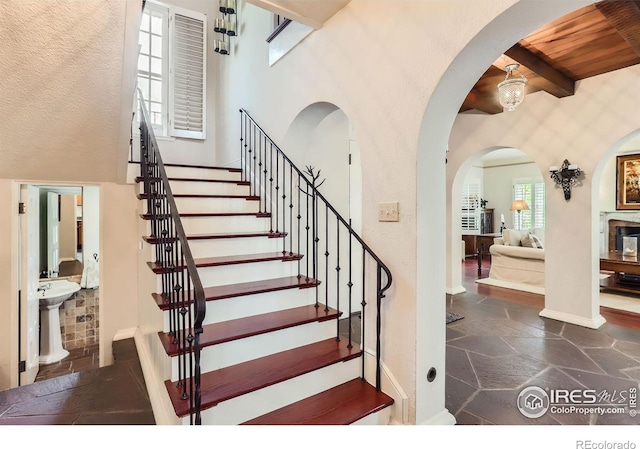 stairway with a towering ceiling and beam ceiling