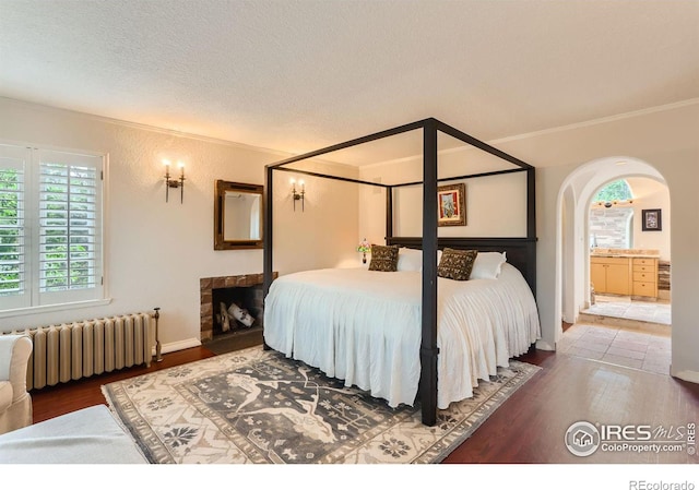 bedroom featuring hardwood / wood-style flooring, ornamental molding, radiator heating unit, and a textured ceiling