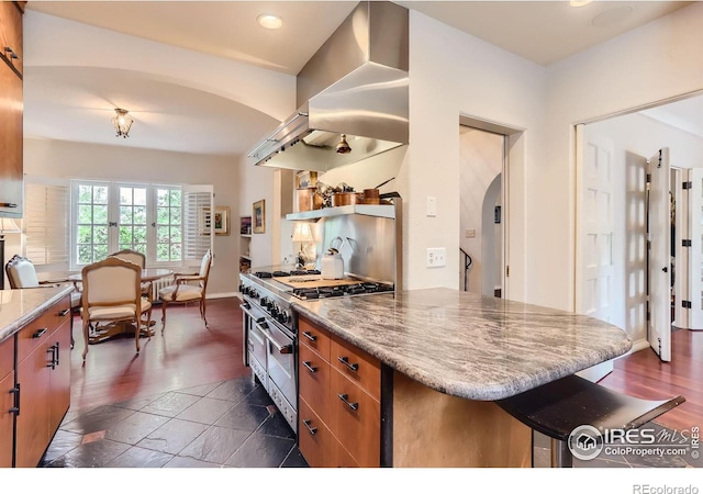 kitchen with dark hardwood / wood-style floors, double oven range, a kitchen breakfast bar, and island range hood