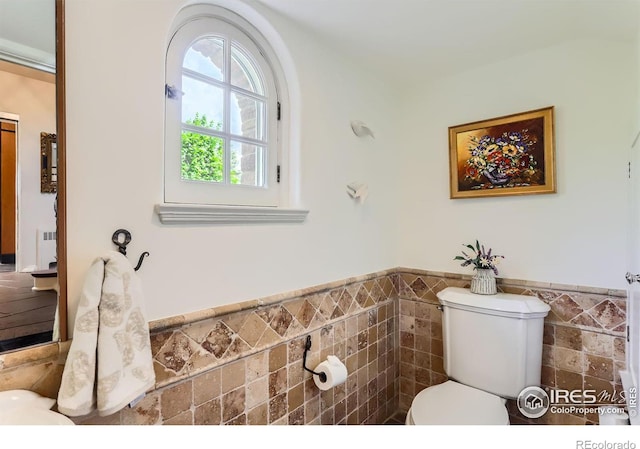 bathroom with tile walls, radiator, and toilet