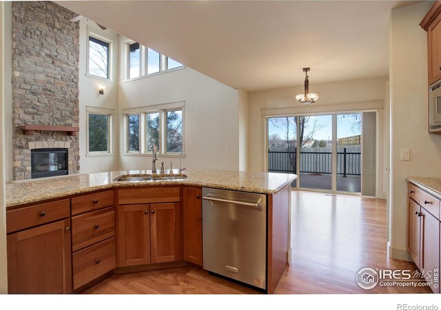 kitchen featuring light stone counters, sink, appliances with stainless steel finishes, and a stone fireplace