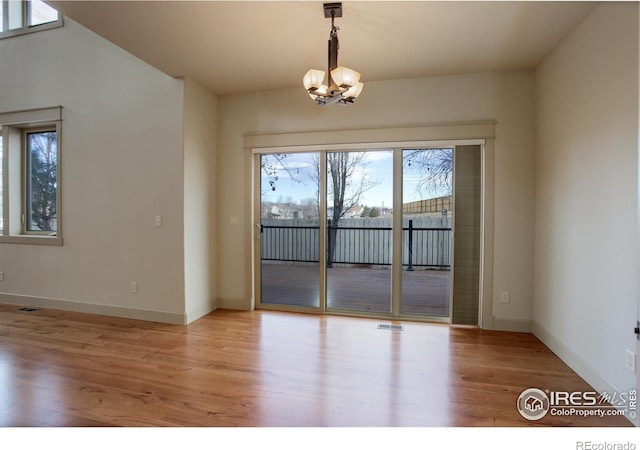 spare room with light wood-type flooring and a chandelier