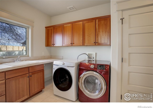 laundry area with light tile patterned floors, sink, washing machine and clothes dryer, and cabinets