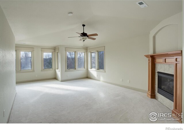 unfurnished living room with ceiling fan, light colored carpet, a tiled fireplace, and lofted ceiling