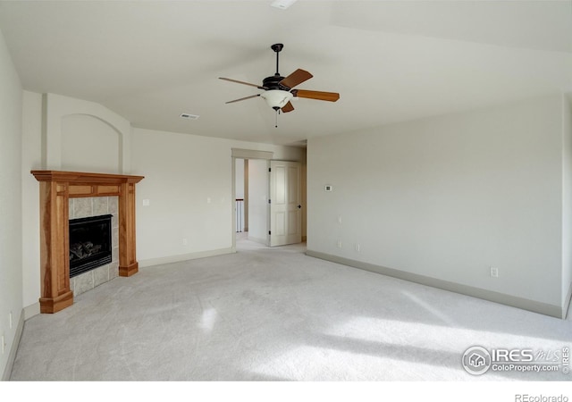 unfurnished living room with ceiling fan, lofted ceiling, and a tiled fireplace