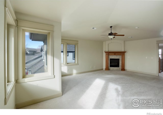 unfurnished living room with light carpet, ceiling fan, and a tile fireplace