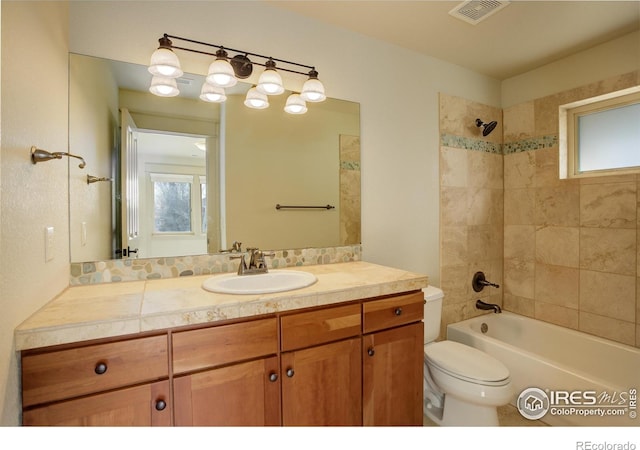 full bathroom with toilet, tiled shower / bath combo, and vanity