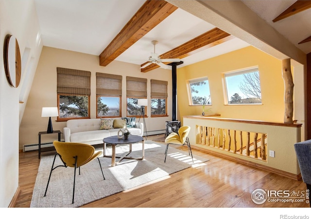 living room featuring a baseboard heating unit, beam ceiling, a wood stove, and light hardwood / wood-style flooring