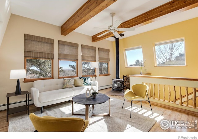 living room featuring a baseboard heating unit, beamed ceiling, a wood stove, and wood-type flooring