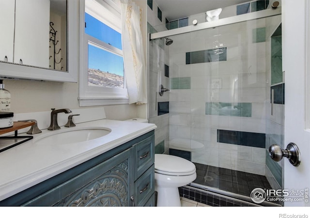 bathroom featuring toilet, a shower with door, and vanity