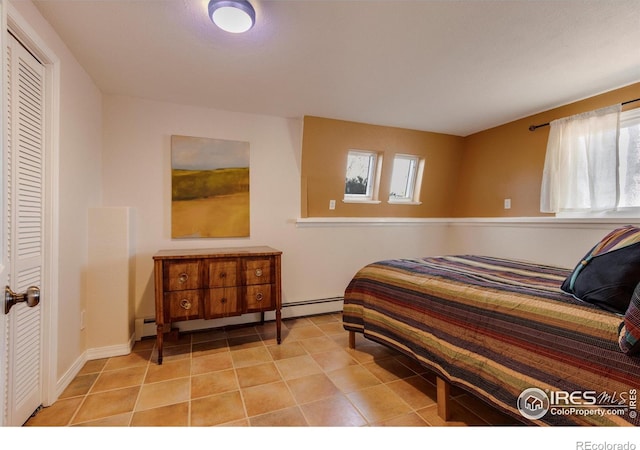 bedroom featuring baseboard heating, light tile patterned floors, and a closet