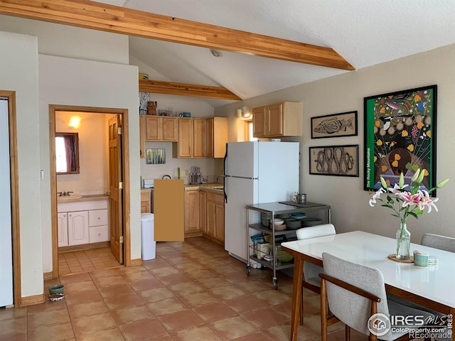 kitchen featuring white fridge, light tile patterned flooring, light brown cabinetry, vaulted ceiling with beams, and sink