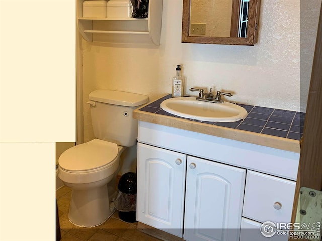 bathroom with toilet, vanity, and tile patterned floors