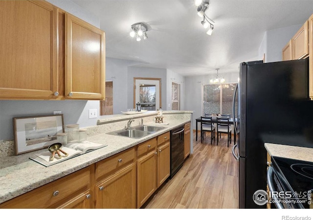 kitchen featuring dishwasher, a notable chandelier, sink, light hardwood / wood-style flooring, and light stone counters