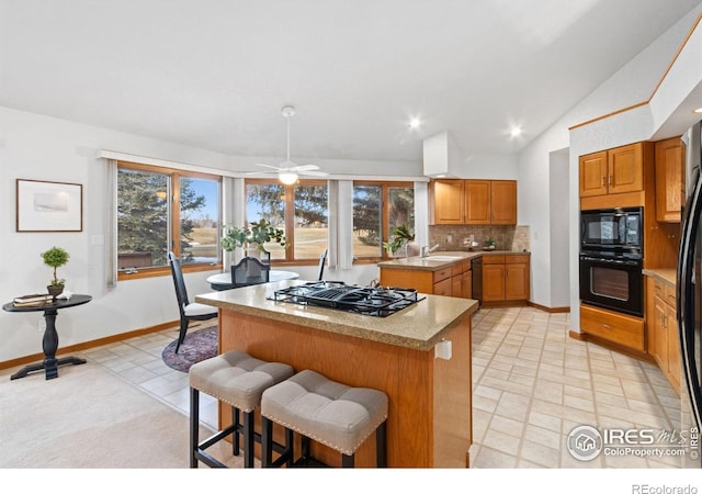 kitchen with lofted ceiling, ceiling fan, backsplash, a kitchen island, and black appliances