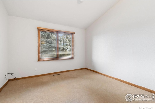 carpeted spare room with vaulted ceiling