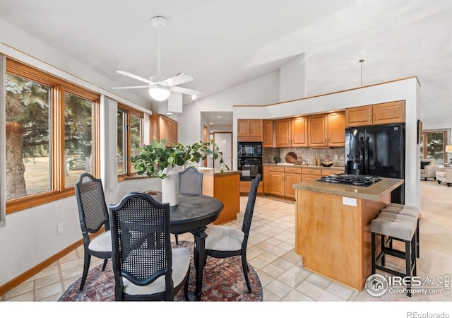 kitchen with ceiling fan, tasteful backsplash, a kitchen island, black appliances, and a kitchen breakfast bar