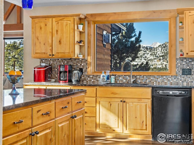 kitchen with sink, dark stone countertops, a wealth of natural light, and black dishwasher