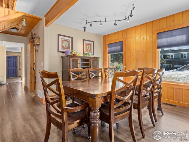 dining area with hardwood / wood-style flooring, rail lighting, and beamed ceiling