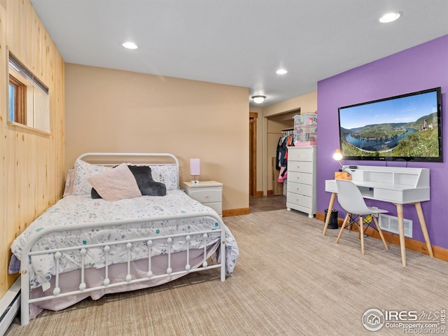 bedroom featuring a closet, light colored carpet, baseboard heating, and wooden walls