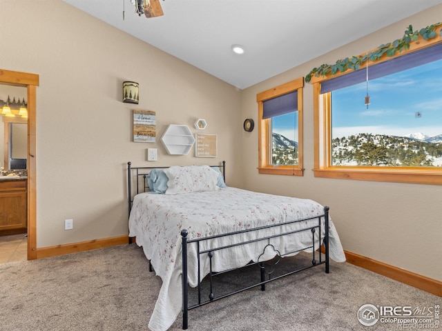 carpeted bedroom featuring a mountain view, ensuite bath, and ceiling fan