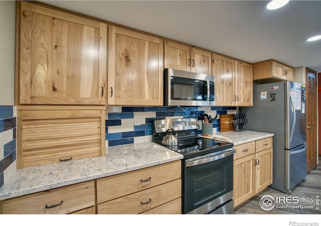 kitchen with appliances with stainless steel finishes, light brown cabinets, backsplash, and light stone counters