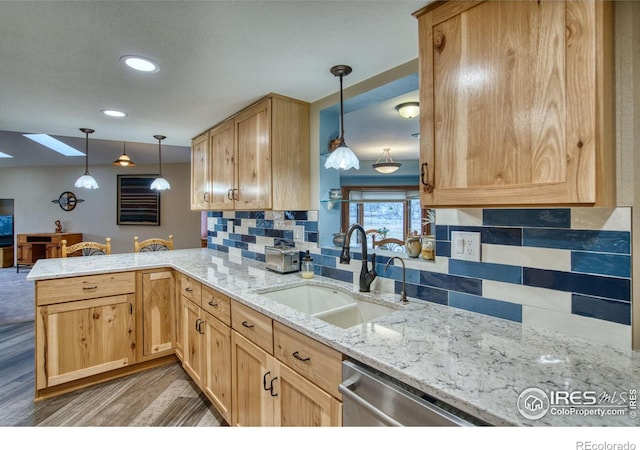 kitchen with sink, hanging light fixtures, wood-type flooring, stainless steel dishwasher, and kitchen peninsula