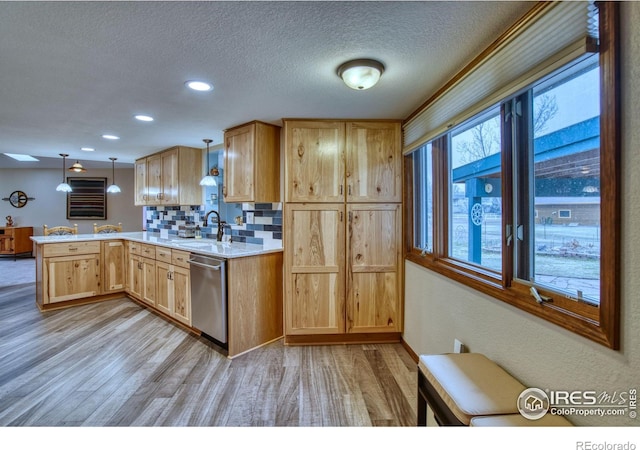 kitchen with hanging light fixtures, tasteful backsplash, light brown cabinetry, stainless steel dishwasher, and kitchen peninsula