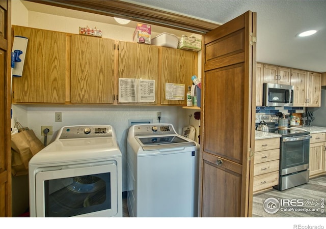 laundry area featuring washer and clothes dryer and light hardwood / wood-style flooring