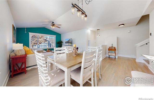 dining space with vaulted ceiling, ceiling fan with notable chandelier, and light hardwood / wood-style flooring