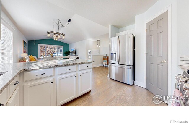 kitchen featuring white cabinets, an inviting chandelier, stainless steel fridge, kitchen peninsula, and vaulted ceiling