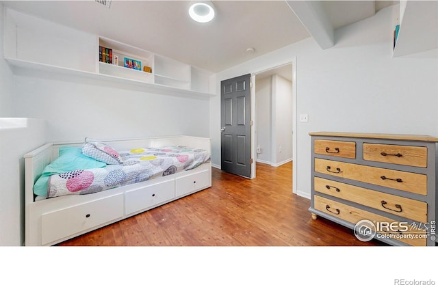 bedroom featuring hardwood / wood-style flooring and beamed ceiling