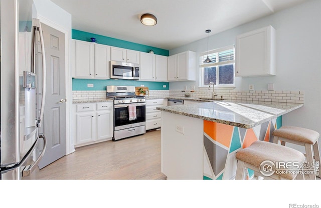 kitchen featuring hanging light fixtures, white cabinets, kitchen peninsula, and appliances with stainless steel finishes