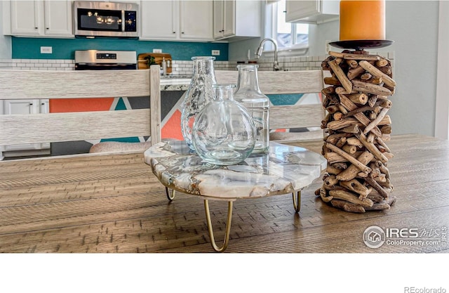 details with appliances with stainless steel finishes, white cabinets, and sink