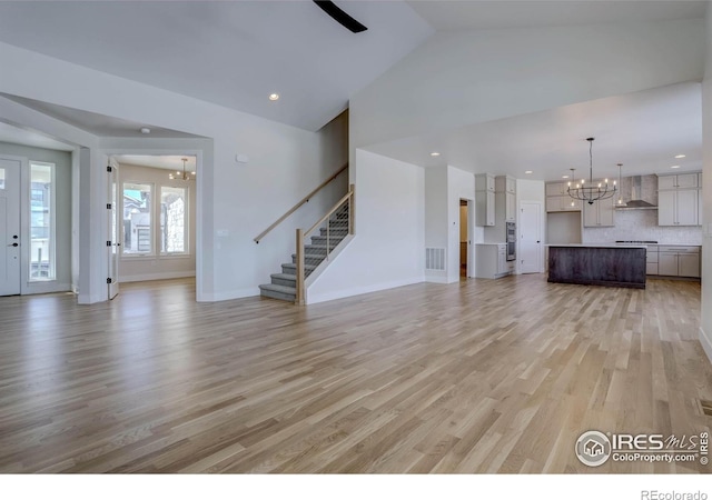 unfurnished living room featuring vaulted ceiling, a chandelier, and light hardwood / wood-style flooring