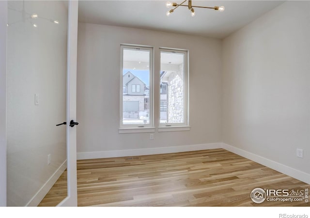 empty room with light hardwood / wood-style flooring and a chandelier