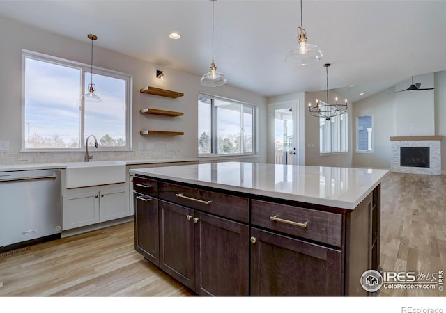 kitchen featuring sink, light hardwood / wood-style flooring, dishwasher, pendant lighting, and decorative backsplash