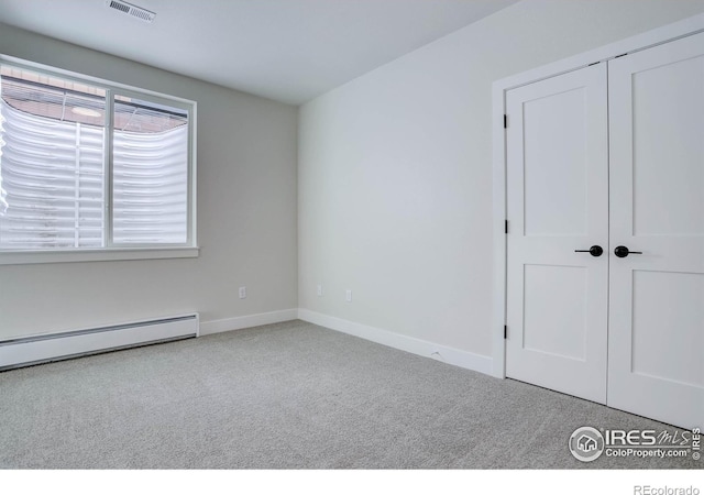 unfurnished bedroom featuring light carpet, a closet, and baseboard heating