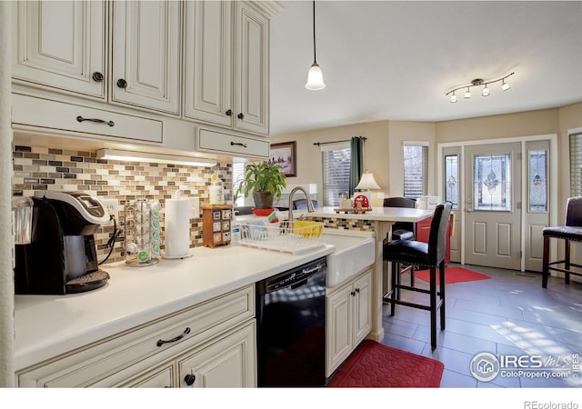 kitchen featuring backsplash, a kitchen breakfast bar, dishwasher, hanging light fixtures, and sink