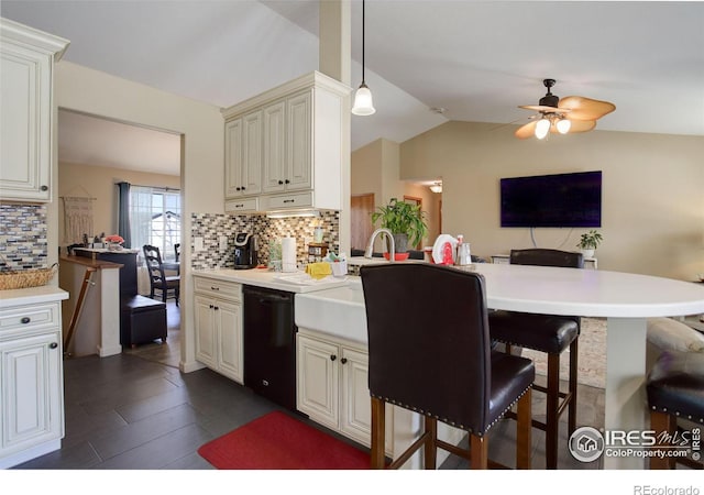 kitchen featuring tasteful backsplash, lofted ceiling, dishwasher, hanging light fixtures, and a kitchen breakfast bar