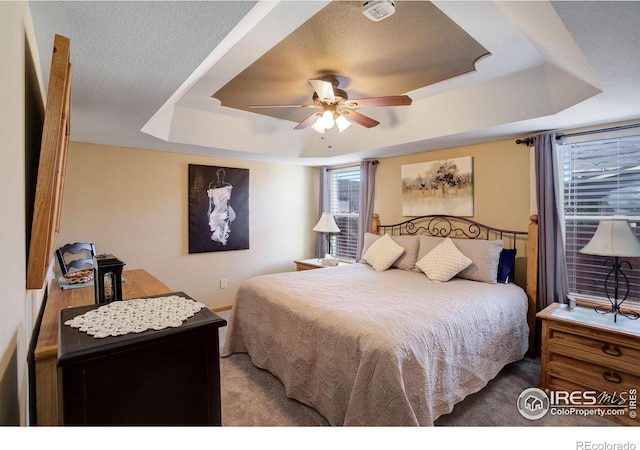 bedroom with ceiling fan, a raised ceiling, and carpet floors