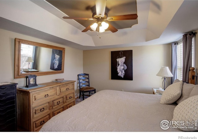 bedroom with ceiling fan and a tray ceiling