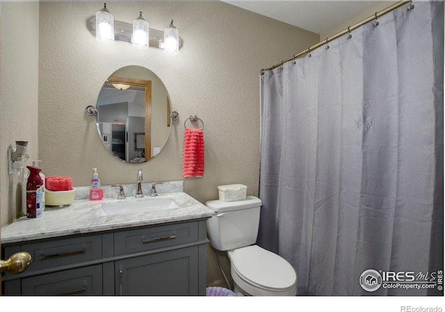 bathroom with curtained shower, toilet, and vanity