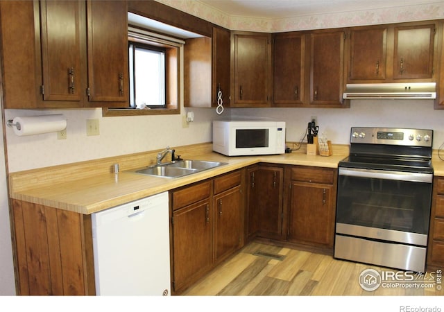 kitchen with white appliances, sink, and light hardwood / wood-style flooring