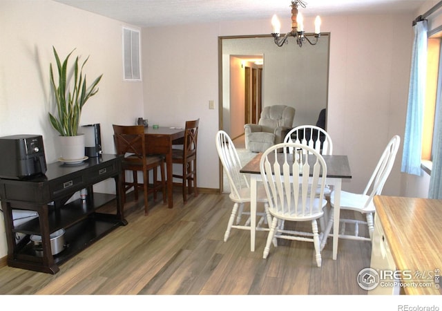 dining area featuring wood-type flooring and a chandelier