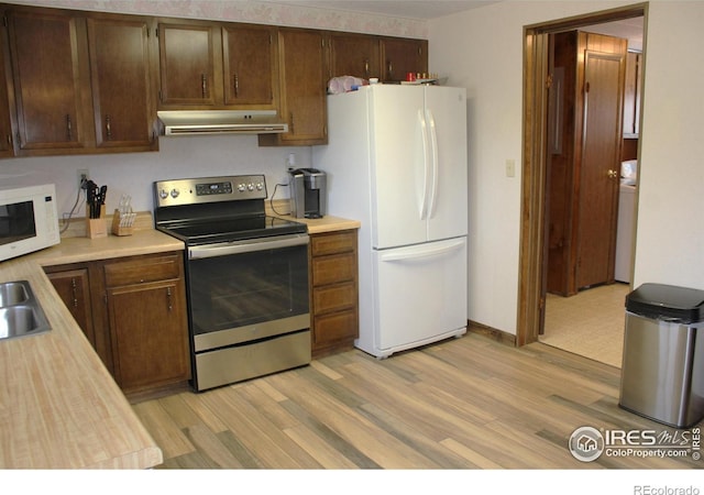 kitchen with white appliances, washer / clothes dryer, sink, and light wood-type flooring