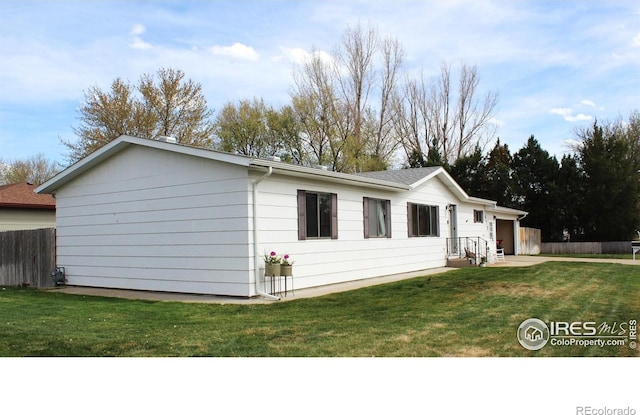 view of property exterior featuring fence, an attached garage, and a yard