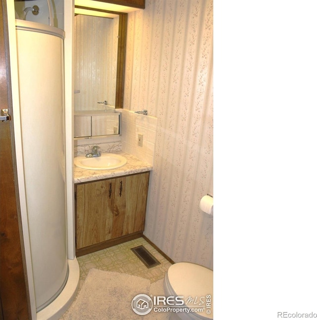 bathroom with visible vents, vanity, toilet, wallpapered walls, and tile patterned floors